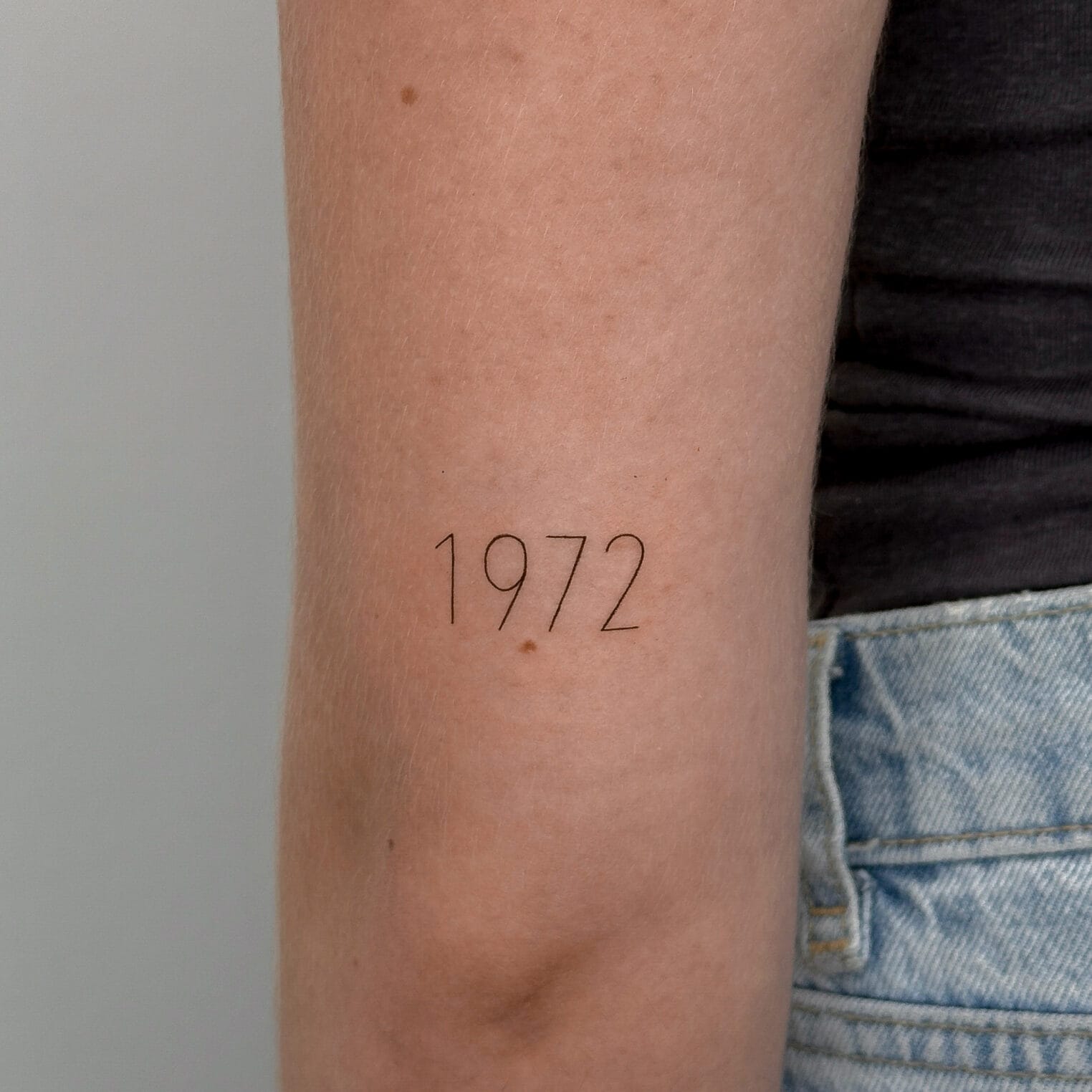 Fine Line Numbers Tattoo Above Elbow