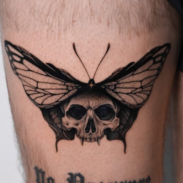 Skull-Faced Butterfly Tattoo Above the Knee