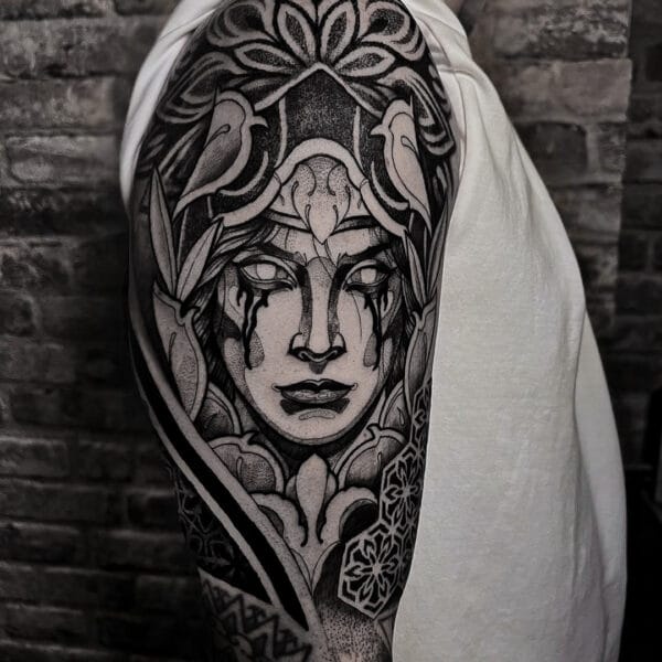 Graphic Portrait Tattoo on Upper Arm with Dot Shading and Ornamental Patterns