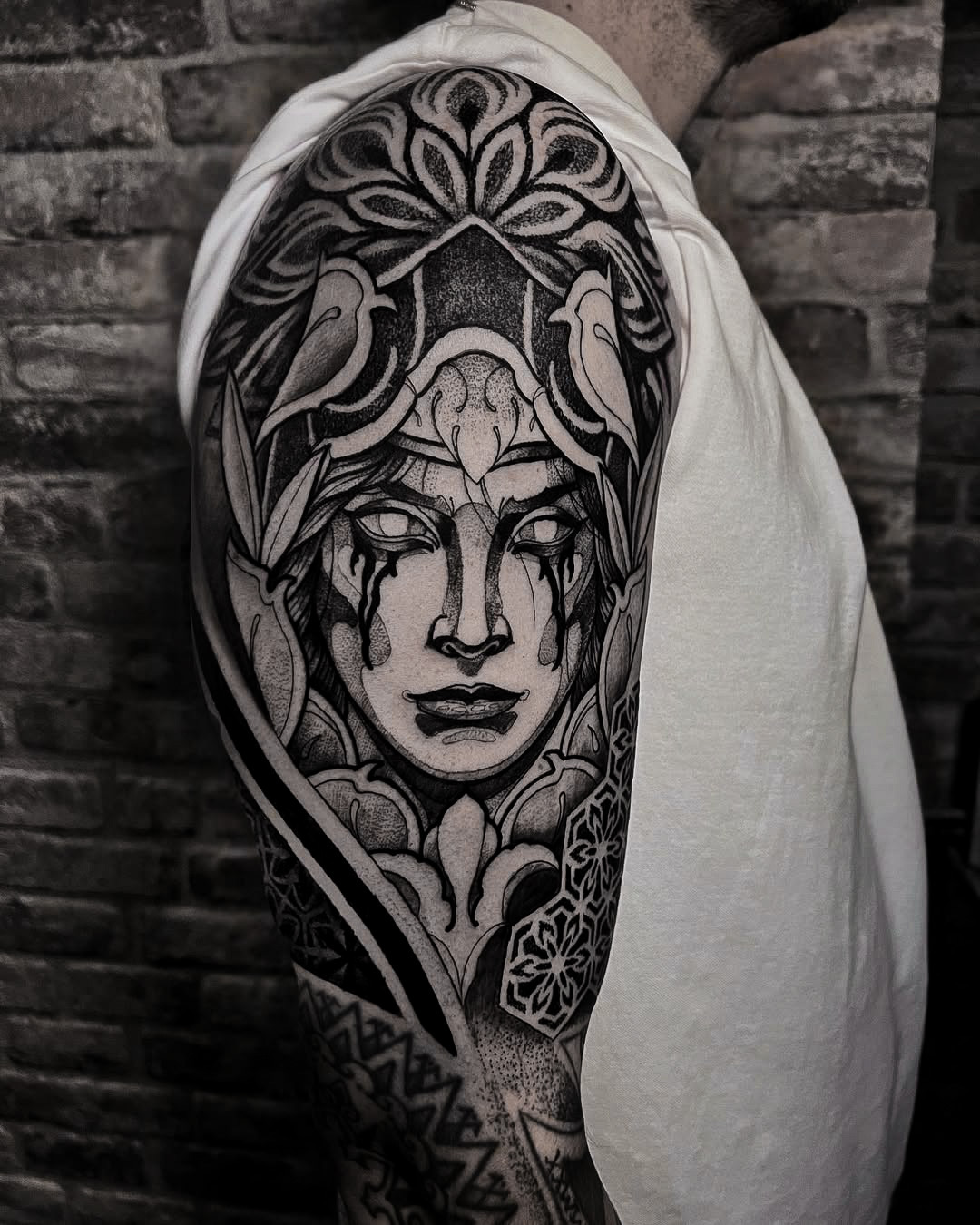 Graphic Portrait Tattoo on Upper Arm with Dot Shading and Ornamental Patterns