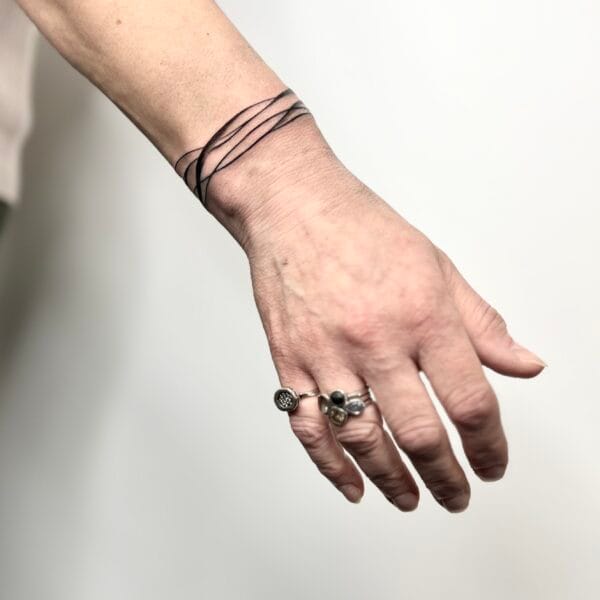 Minimal Black Ink Wrist Tattoo with Abstract Lines