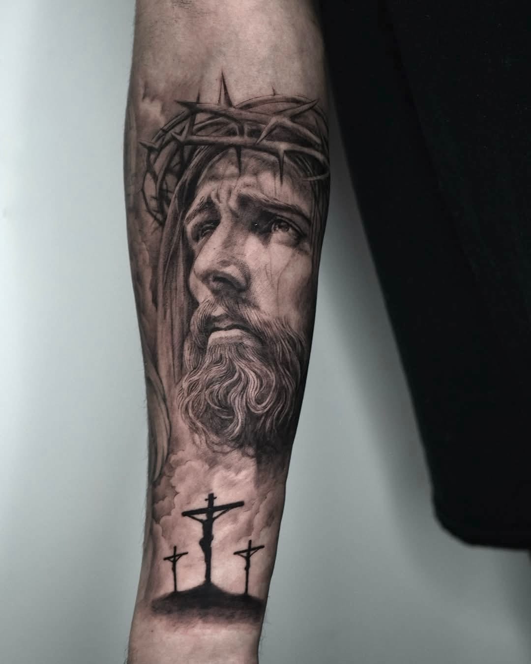 Black And Gray Forearm Tattoo Featuring Jesus And Crosses