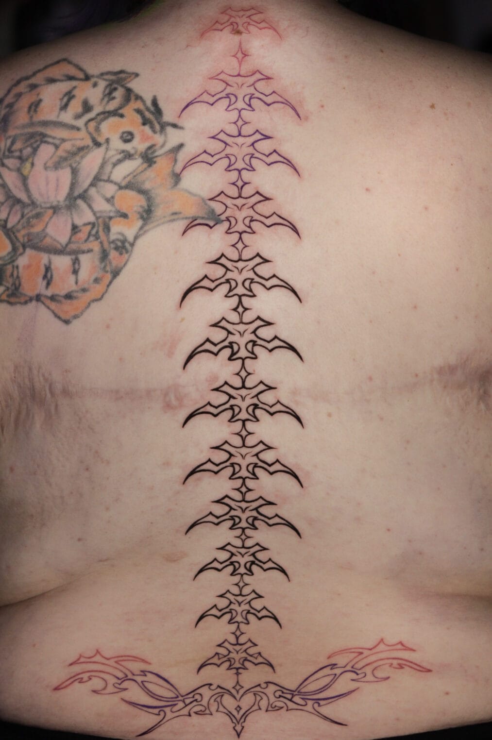 Along the spine neo tribal tattoo aligned with the natural spine line