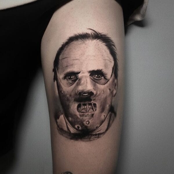 Black And Gray Hannibal Lecter Portrait Tattoo On Thigh