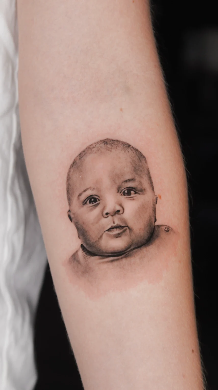 black and gray baby portrait micro realism tattoo los angeles