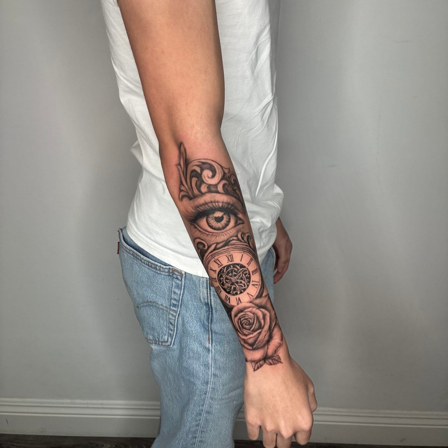 Black And Gray Forearm Tattoo With Eye, Clock And Rose