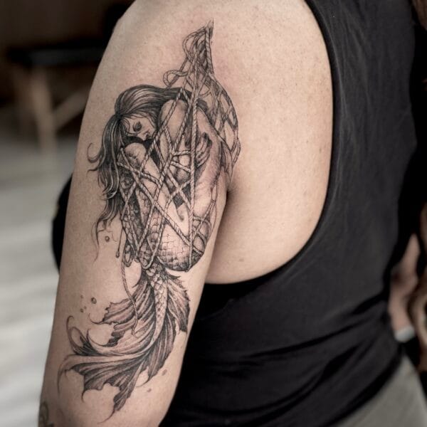 Realistic Black And Gray Mermaid Tattoo On The Arm With Mesh